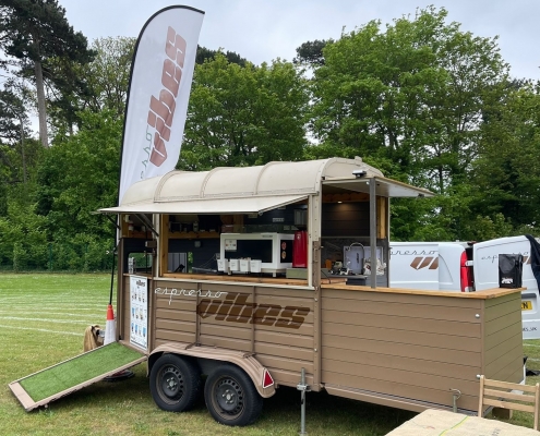 A brown Espresso Vibes trailer with the hatch open ready to sell coffee
